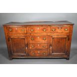 A George III oak low dresser, with an arrangement of six drawers and two cupboards, with bone