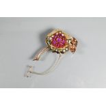 A floral spray brooch of pink, yellow and white unmarked metal set with nine pink sapphire/ruby