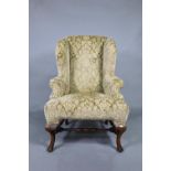 An oak framed upholstered Wing armchair, 19th century, raised on cabriole front legs united by