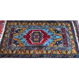 A Turkish light blue ground rug with centred with gold ground lozenge design, 234 cm x 132 cm