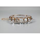 A Victorian oval half-hinged bangle of open wirework form, set with seven graduated circular