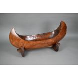 An Indonesian stained and hollowed hardwood fruit bowl on stand in the form of a dugout canoe, 65 cm