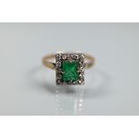 An emerald and diamond cluster ring, the central rectangular cut emerald with diamond surround,