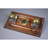 A brass mounted oak ink stand, with two glass bottles and centred by an engraved shield 'Compliments