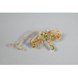 An Art Nouveau open scroll brooch set overall with half pearls and four various peridots, 15ct