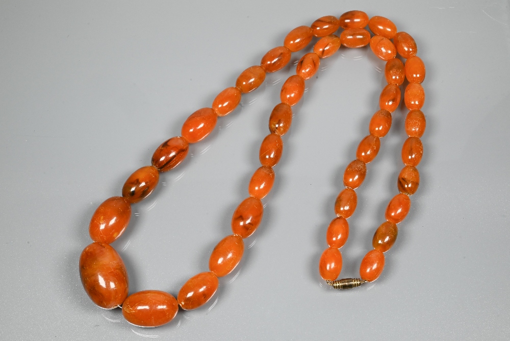 A graduated row of amber beads, 3 x 2 cm the largest bead, 1 x 0.7 cm the smallest, approx 64g all