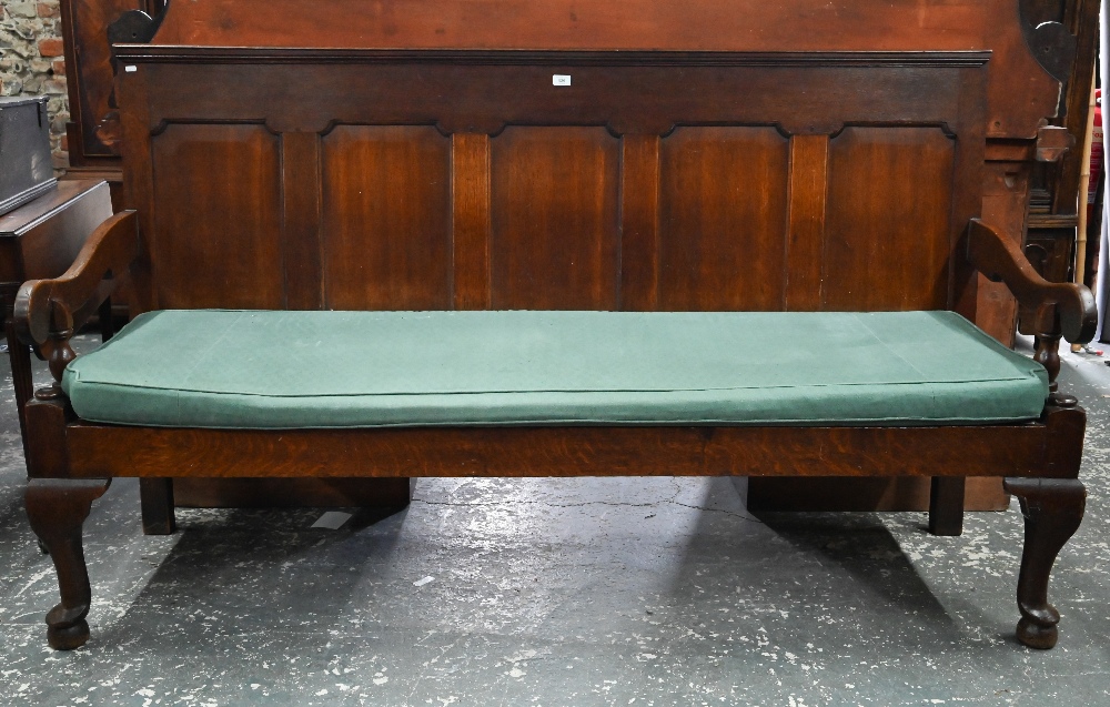 An 18th century oak panel backed settle, with shaped arms over a rope and canvas seat (cushion