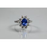 An oval cluster ring, the central oval tanzanite (possibly) surrounded by ten claw set diamonds,