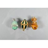 Three various egg-shaped pendants - one pale green hardstone, one green and pale yellow enamel,