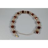 A garnet set bracelet, the rectangular garnet set links interspersed with circular chain links,