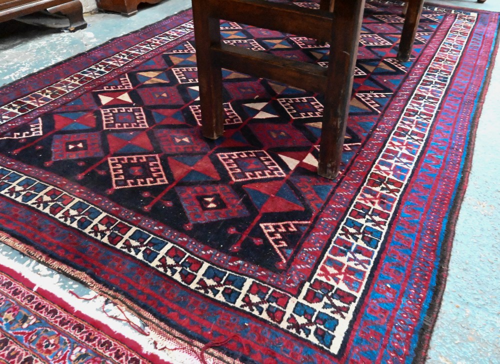 A Persian blue/red ground geometric design rug, 258 cm x 166 cm