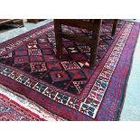 A Persian blue/red ground geometric design rug, 258 cm x 166 cm