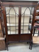 A 20th century mahogany display cabinet with a moulded cornice above two glazed doors with glazed