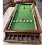 A table top bar billiards table, with eight holes, balls, cues and scoreboard,
