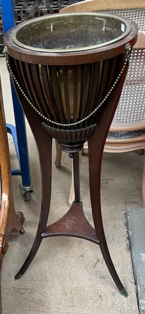 A mahogany jardiniere with a brass inset and stick sides on three splayed legs