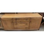 A mid 20th century Ercol teak sideboard with a rectangular top above three central drawers and two