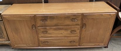 A mid 20th century Ercol teak sideboard with a rectangular top above three central drawers and two