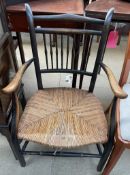 An Arts and Crafts style elbow chair with a spindle back and rush seat