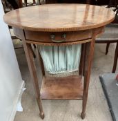 An Edwardian mahogany work table with an oval top above a sectional drawer and pull out slide on