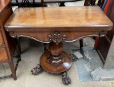A Victorian rosewood card table with a foldover top and baize interior above a shaped front on a