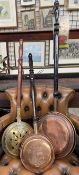 A copper bedwarming pan together with a brass bedwarming pan and a small copper example