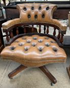 A modern brown leather office swivel chair with button back upholstery on four legs