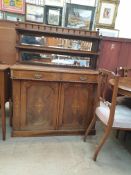 A Victorian walnut chiffonier with a spindle rail above two shelves and a mirrored back,