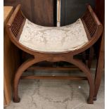 An Edwardian mahogany stool of dished shape with spindle sides and a pad seat on an X frame