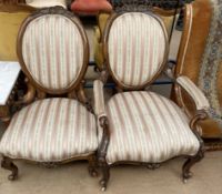 A pair of Victorian walnut framed chairs including a lady's and gentleman's chair with striped