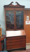 An Edwardian mahogany bureau bookcase the cornice with a broken Swan Neck pediment and a pair of