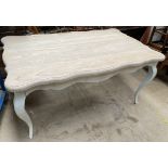 A modern cream painted dining table with a shaped top on cabriole legs