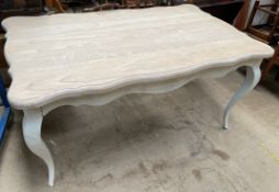 A modern cream painted dining table with a shaped top on cabriole legs