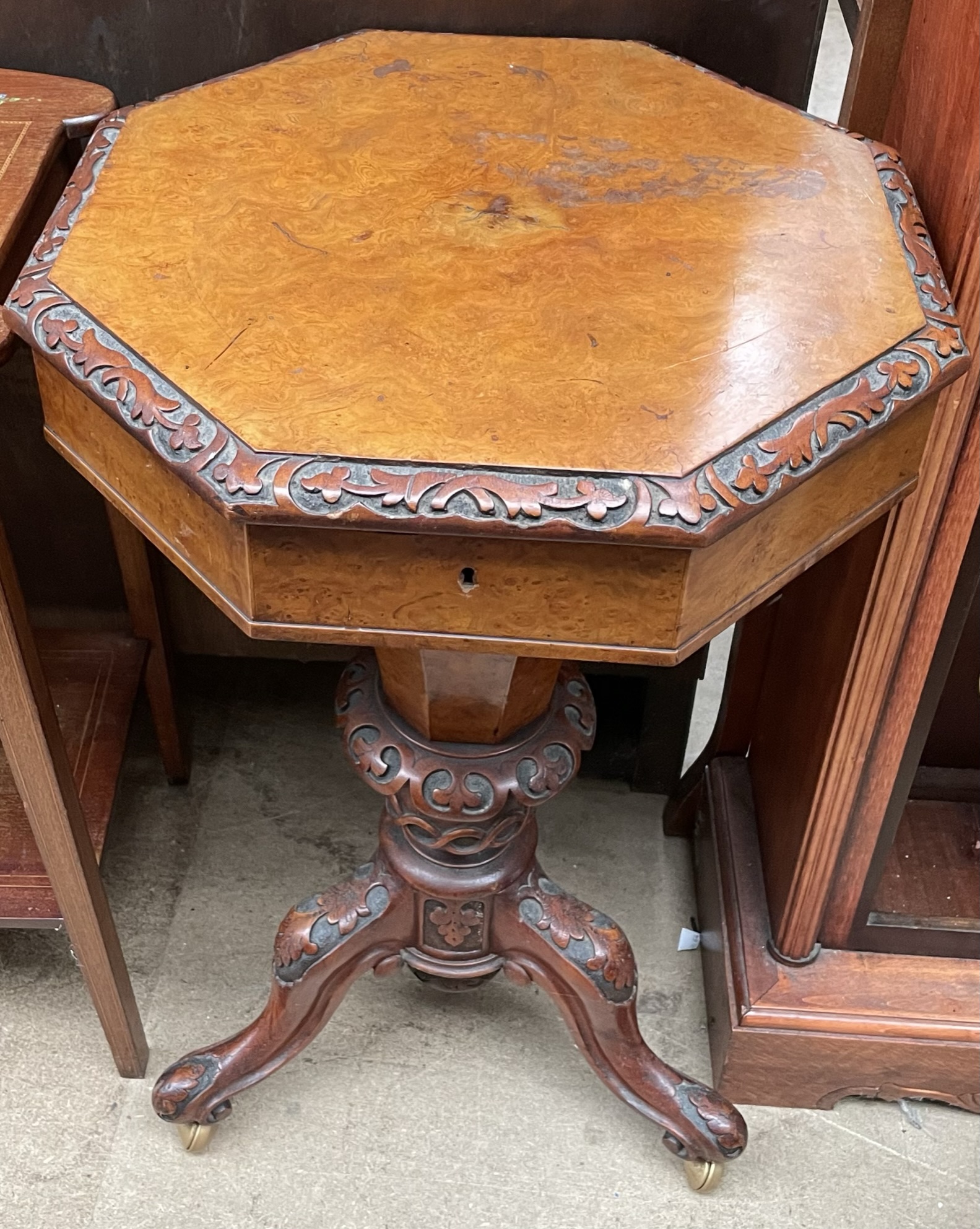 A Victorian walnut work table with an octagonal top and central well on a carved tripod base