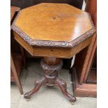 A Victorian walnut work table with an octagonal top and central well on a carved tripod base