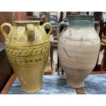 A studio pottery vase with four handles and a mustard yellow glaze and stylised flowers together