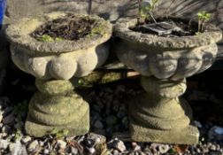 A pair of reconstituted stone urn planters on a pedestal base