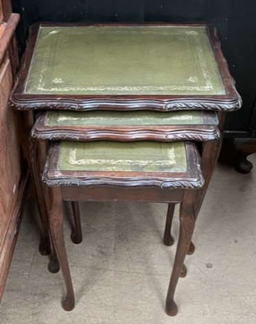 A nest of three tables with leather inset top