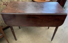 A Victorian mahogany Pembroke table with drop flaps on ring turned tapering legs