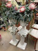 A pair of pottery urns on matching stands