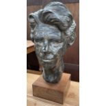 A bronzed portrait bust of a lady's head on a square plinth