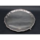 A George V silver salver with a shaped gadrooned border, on claw and ball feet,