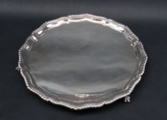 A George V silver salver with a shaped gadrooned border, on claw and ball feet,