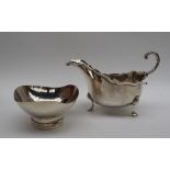 A George V silver sauce boat, with a shaped rim and scrolling handle on three legs, London, 1915,
