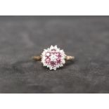 A 9ct gold ruby and diamond cluster ring, set with a central round brilliant cut diamond,