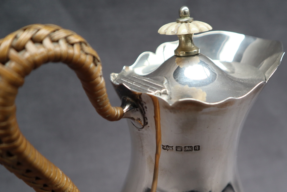 An Edward VII silver hot water jug with a flared edge and baluster body on three legs with trefid - Image 2 of 5