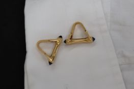 A pair of Boucheron of Paris yellow metal cufflinks of stirrup form with sugarloaf sapphire