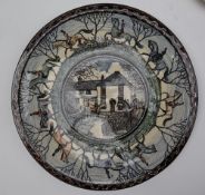 A stoneware plate, painted with Huntsman and hounds to the border, the centre with a village scene,
