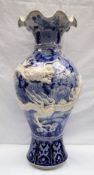 A Japanese blue and white porcelain vase decorated with a raised dragon encircling the vase further