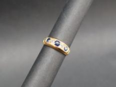 A sapphire and diamond ring set with three round faceted sapphires and two round old cut diamonds