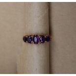 A 9ct yellow gold amethyst line ring set with five graduated oval amethysts to a claw setting and